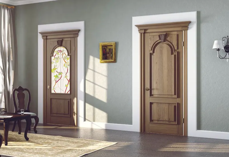 Gri duvarlı salonda biri vitray camlı, biri kemerli panelli iki klasik ahşap kapı