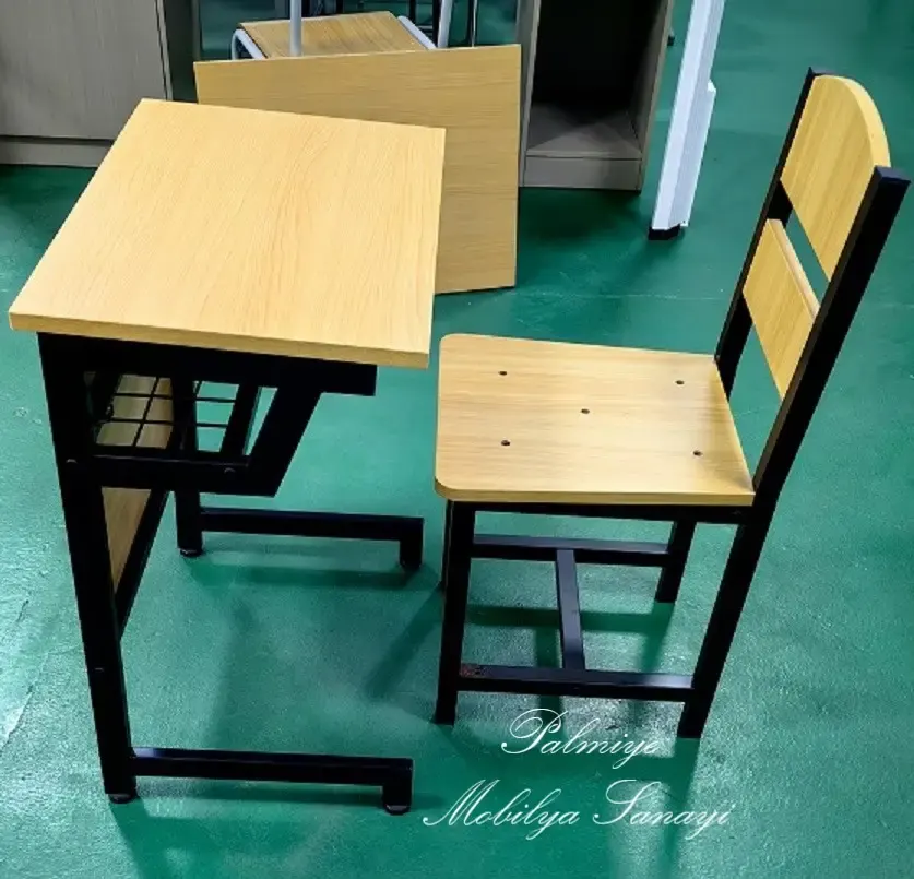 Yeşil zeminde ahşap tonlu tablalı tek kişilik okul sırası ve metal ayaklı sandalye