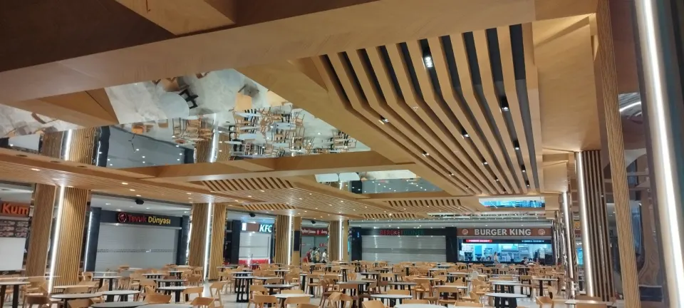 Ahşap kaplı kirişler ve aynalı tavan arasından restoran tezgahlarına uzanan yemek alanı
