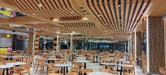 Dalgalanan ahşap çıtaların altında uzanan geniş masa düzeniyle restoran alanı