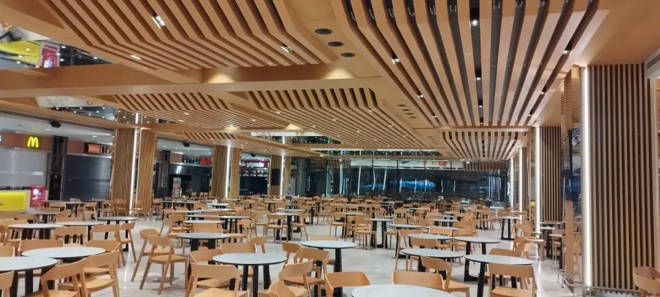 Ahşap çıta tavan altında cam cepheye kadar dizilen yuvarlak masalar ve ahşap sandalyeler