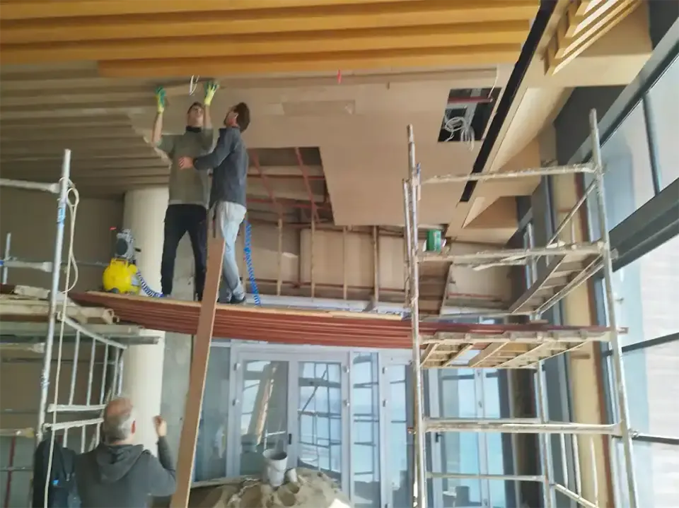 Lüks otel mobilyaları yazısında iskele üzerinde ahşap tavan paneli monte eden ustalar