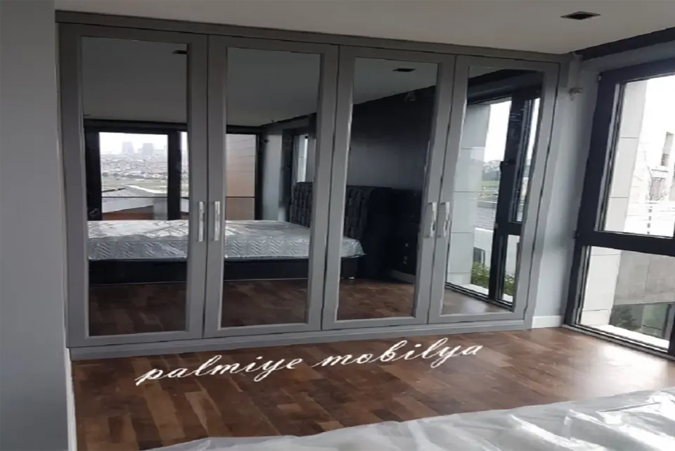 Gri çerçeveli aynalı gardırop kapaklarında yatak odasının yansıması