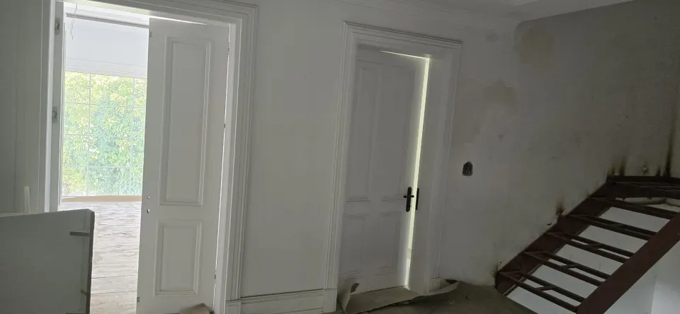 Villa merdiven sahanlığına açılan iki beyaz panel kapı ve metal merdiven iskeleti