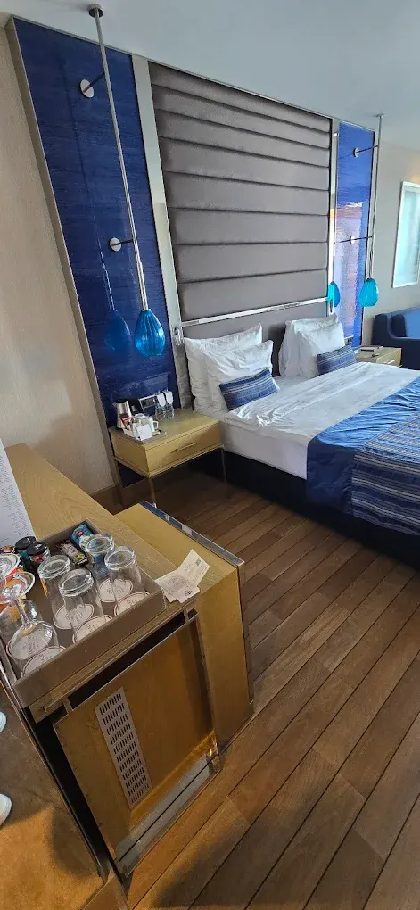 Otel projesine özel üretilmiş lacivert başlıklı yatak, ahşap komodin ve minibar ünitesi
