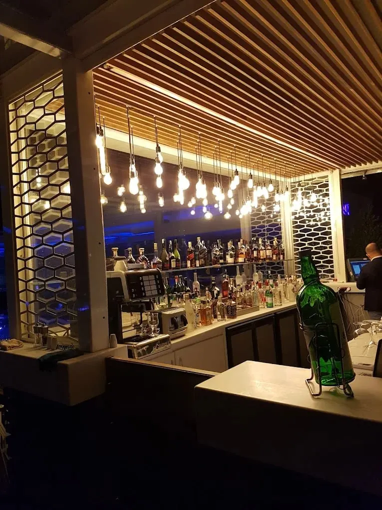 Otel restoran mobilyaları arasında ahşap çıtalı tavanlı bar, petek desenli paneller ve sarkıt ampuller